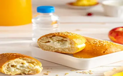 Lancheira escolar aberta com pães de queijo proteicos dourados, um deles aberto mostrando recheio de requeijão cremoso.