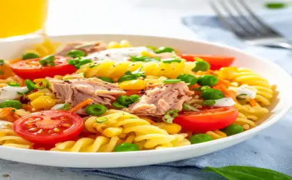 Tigela com salada de macarrão parafuso, atum, tomate cereja e molho de iogurte cremoso sobre toalha azul. Jantar Sem Forno